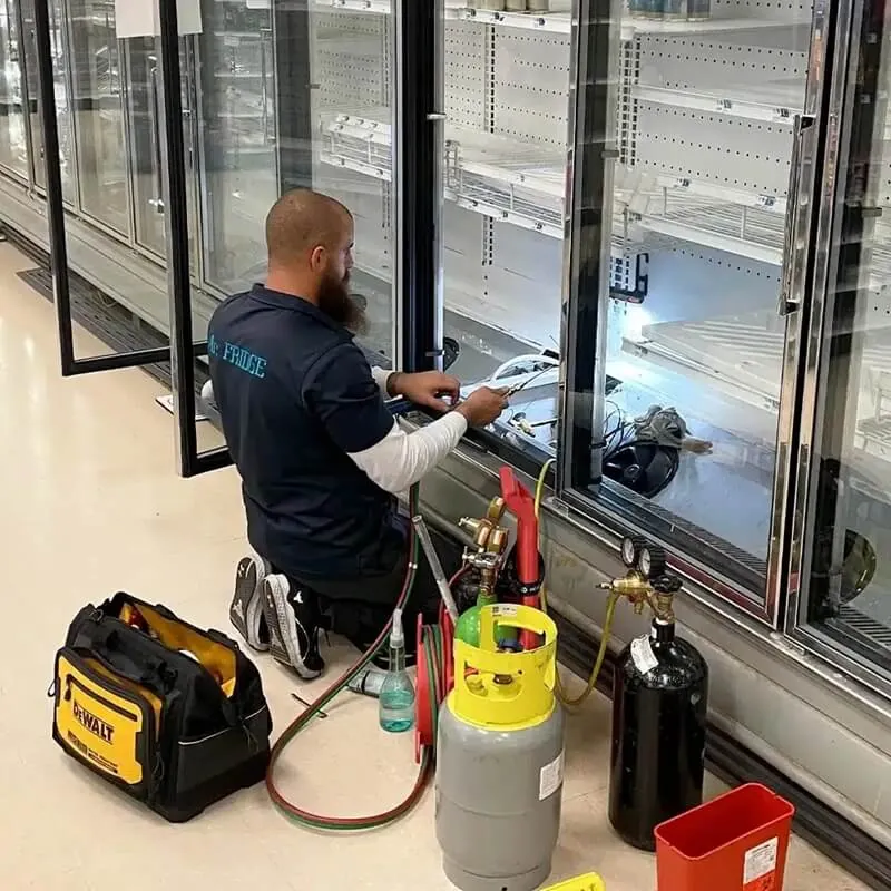 Appliance Repair Hero technician recharging a commercial reach-in refrigerator at a business